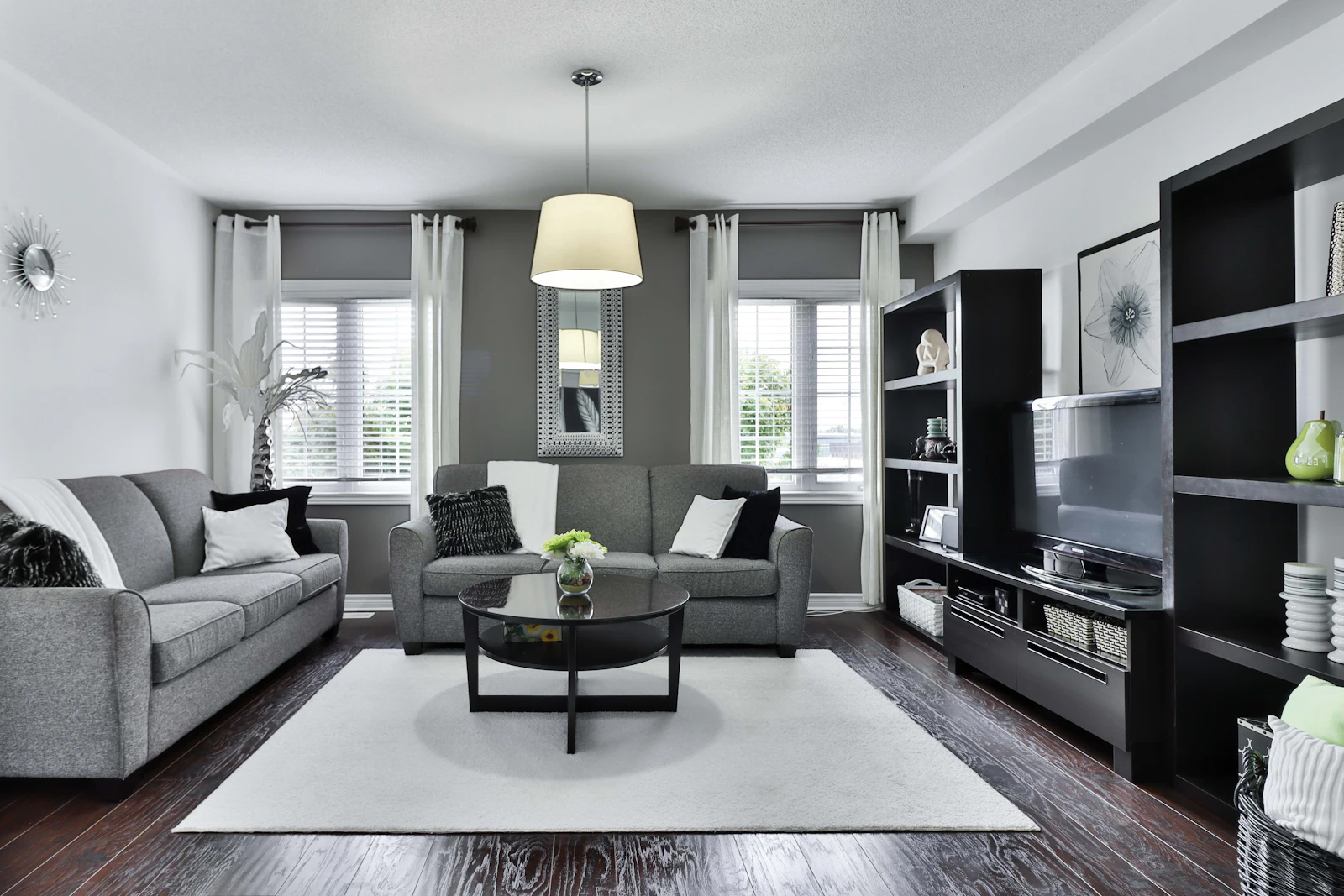 A grey-toned living room with twin sofas and shuttered windows. Illustrative photography.